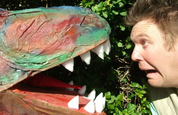 Actor looking worryingly into mouth of T-rex