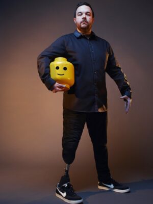 Colin Leggo stands boldly whilst holding a giant Lego head
