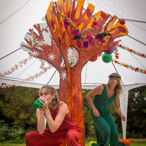 Two actors, in costume, perform around a cardboard tree.