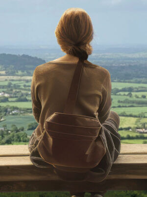 A young lady looks out across a vast countryside landscape.
