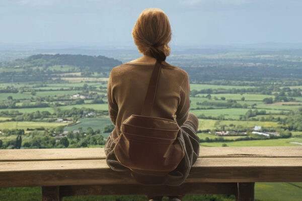 A young lady looks out across a vast countryside landscape.
