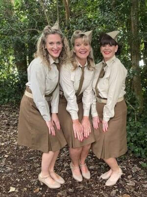 The Ritzy Belles pose in costume in front of the greenery at Penlee Park.
