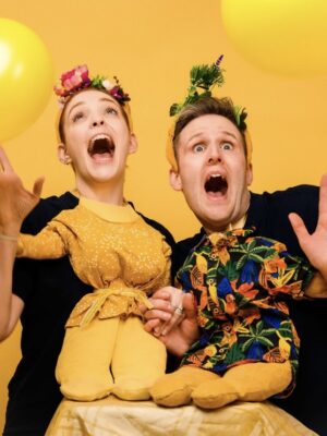 Titania and Oberon look surprised as two yellow balloons float in the foreround.