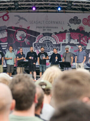 Long distance shot of the Oggymen performing on stage at Falmouth Sea Shanty Festival.